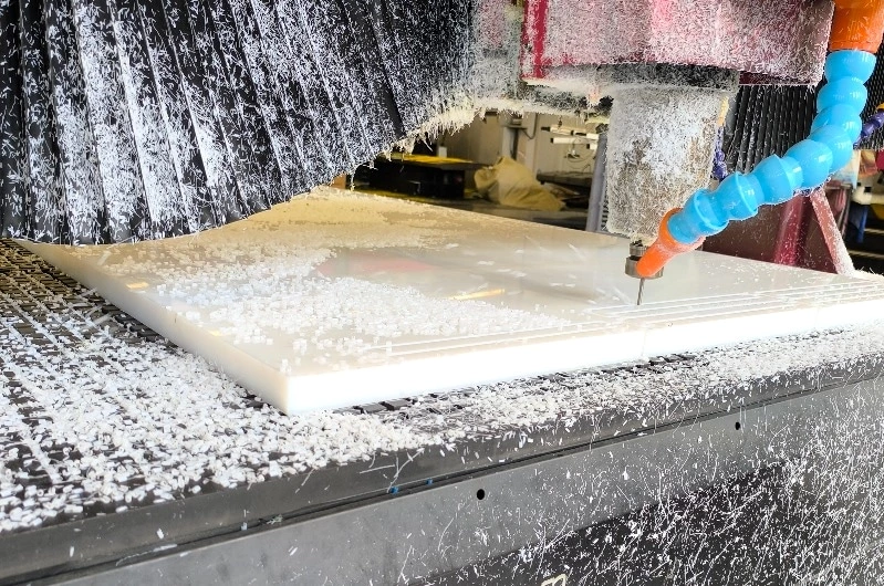 Partially machined UHMWPE block on CNC machine bed with visible tool paths
